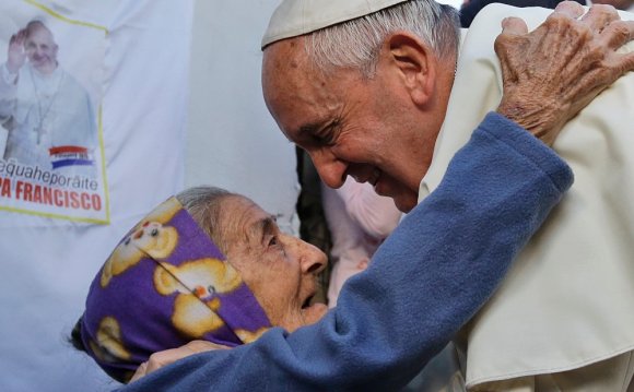 An elderly woman greets the