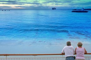 any senior couple look out on the beach toward their cruise ship